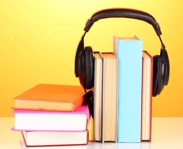 Kopfhörer auf Büchern auf orangefarbenem Hintergrund — Stockfoto