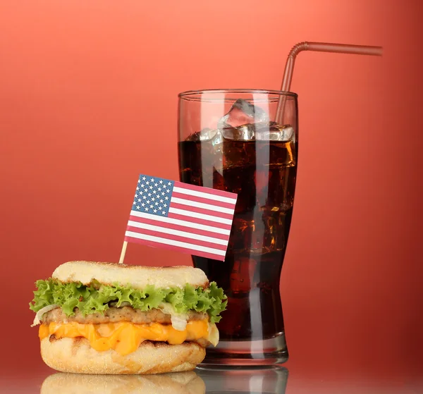 Tasty sandwich with american flag and cola, on red background — Stock Photo, Image