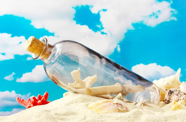 青い空を背景に、砂の上の内部メモのガラス瓶 — ストック写真