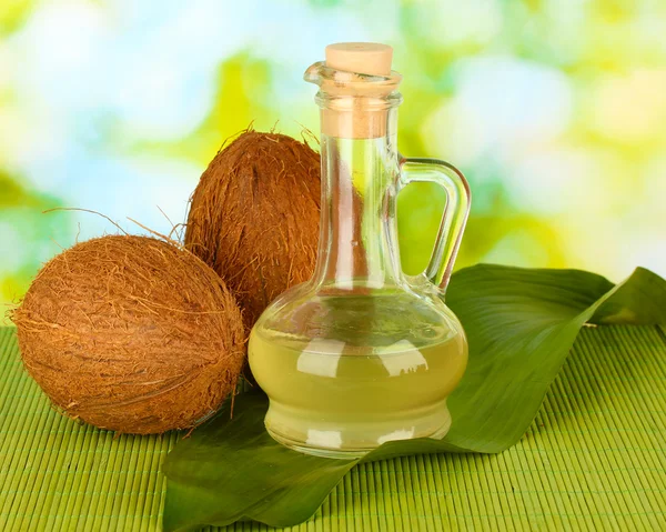 Decantador con aceite de coco y cocos sobre fondo verde —  Fotos de Stock