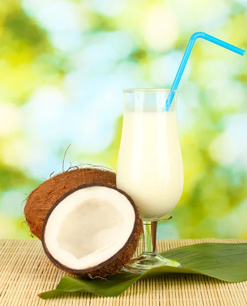 Glass of coconut milk and coconuts on green background close-up — Stock Photo, Image