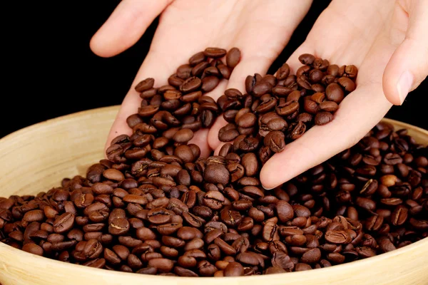 Grãos de café nas mãos sobre fundo escuro — Fotografia de Stock