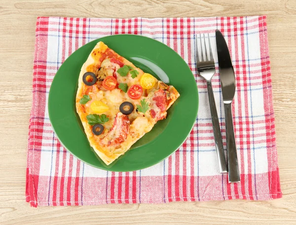 Piatto con una fetta di deliziosa pizza su fondo di legno — Foto Stock