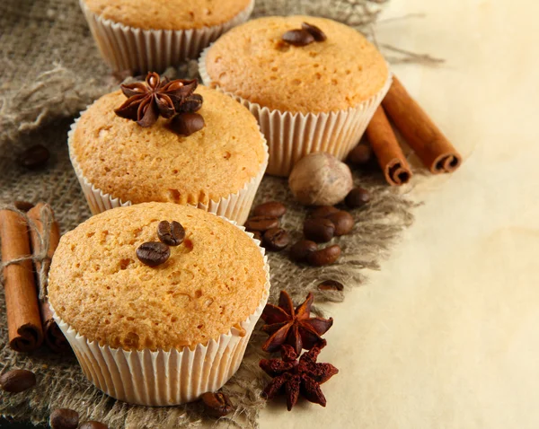 Savoureux muffins sur toile de jute, épices et graines de café, sur fond beige — Photo