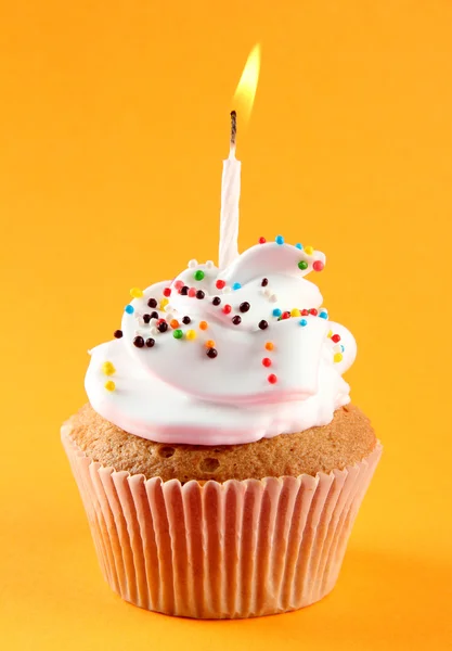 Вкусный день рождения кекс со свечой, на оранжевом фоне — стоковое фото