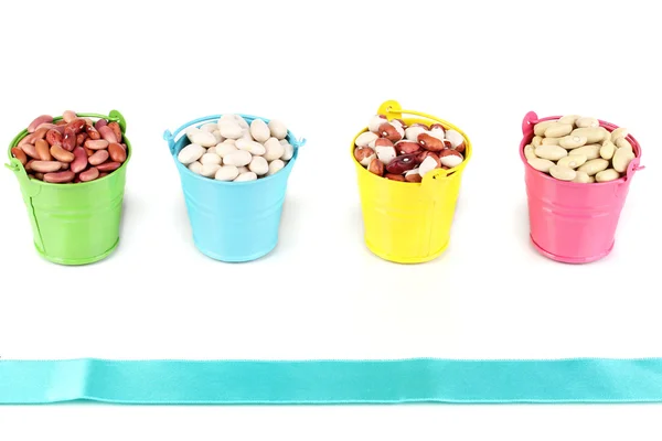 Diferentes tipos de frijoles en cubos de colores aislados en blanco —  Fotos de Stock