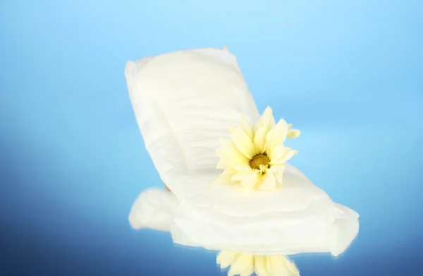 Panty liner and yellow flower on blue background close-up — Stock Photo, Image