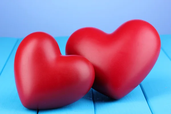 Coeurs rouges décoratifs sur table en bois bleu sur fond bleu — Photo