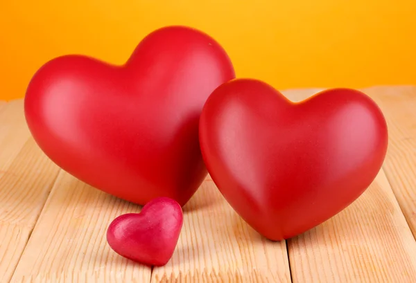 Turuncu zemin üzerine ahşap masa üstünde kırmızı dekoratif Kalpler — Stok fotoğraf