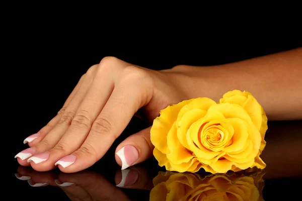 Gele roos met vrouw hand op zwarte achtergrond — Stockfoto