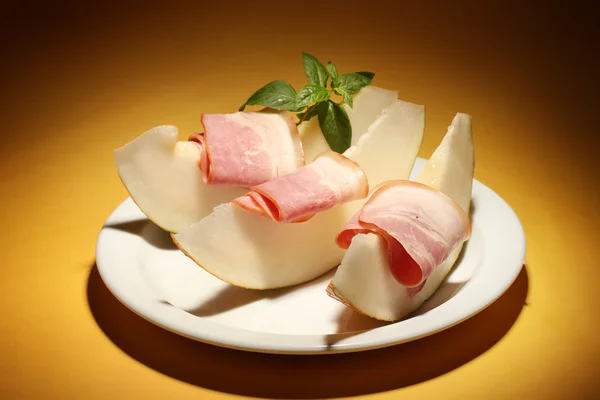 Parma ham and melon, on yellow background — Stock Photo, Image