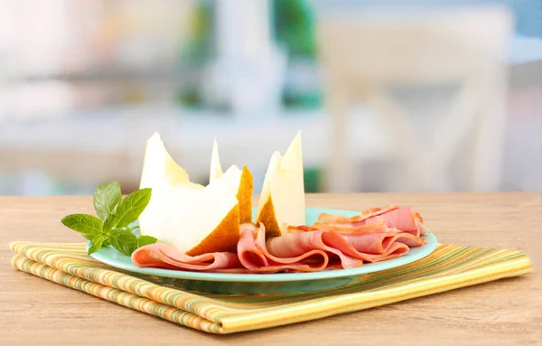 Parma ham and melon, on wooden table — Stock Photo, Image