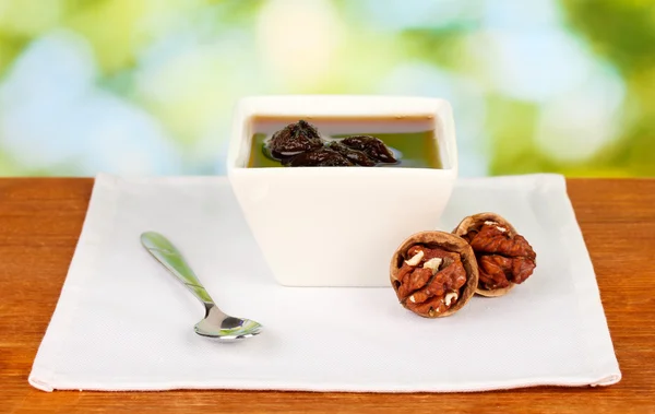 Jam, walnuts in a bowl on a table on a green background — Stock Photo, Image