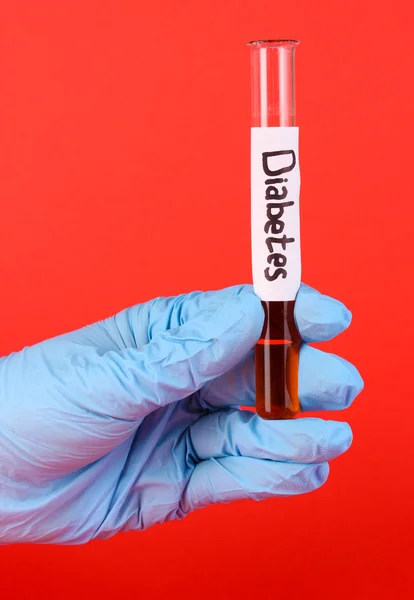 Kémcsőbe feliratú cukorbetegség, kezében piros háttér — Stock Fotó