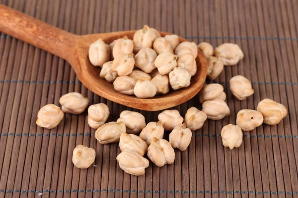 White chickpeas over wooden spoon on color background — Stock Photo, Image