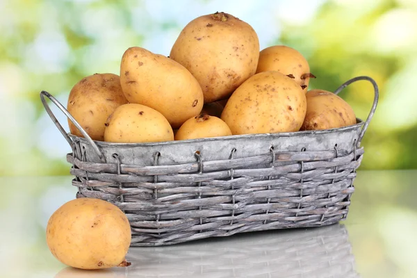 Reife Kartoffeln auf Korb auf Tisch vor natürlichem Hintergrund — Stockfoto