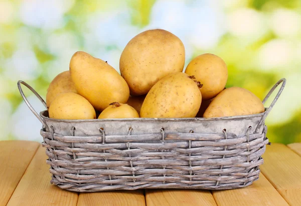 Rijp aardappelen op de mand op houten tafel op natuurlijke achtergrond — Stockfoto