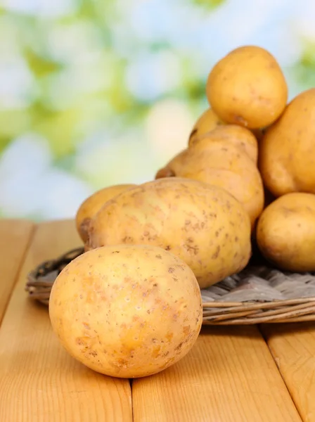 Rijp aardappelen op rieten wieg op houten tafel op natuurlijke achtergrond sluiten- — Stockfoto