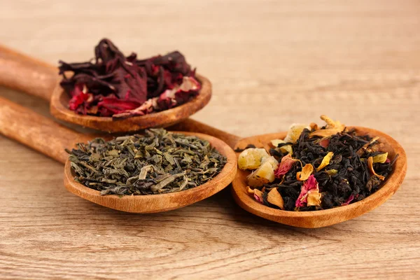 Assortment of dry tea in spoons, on wooden background — Stock Photo, Image