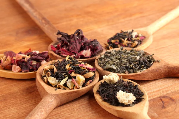 Assortment of dry tea in spoons, on wooden background — Stock Photo, Image