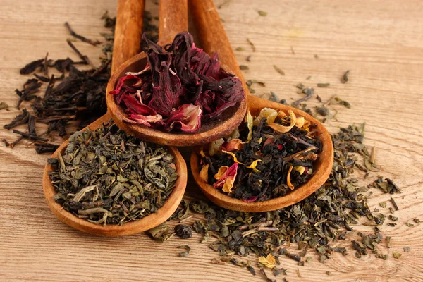 Assortment of dry tea in spoons, on wooden background — Stock Photo, Image