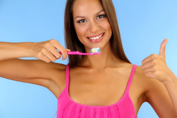 Mulher bonita com escova de dentes no fundo azul — Fotografia de Stock