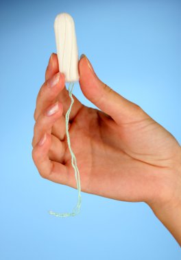 woman's hand holding a clean cotton tampon on blue background close-up clipart