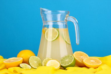 narenciye çevresinde mavi sarı kumaş üzerine cam sürahi içinde narenciye limonata