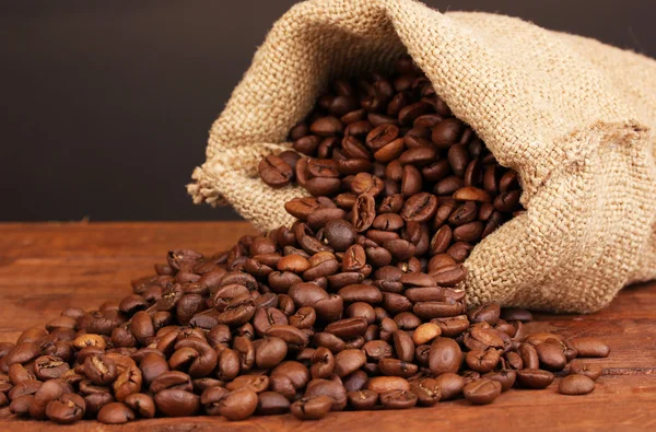 Koffie bonen in zak op tafel op donkere achtergrond — Stockfoto