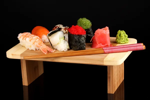 Heerlijke sushi geserveerd op een houten bord geïsoleerd op zwart — Stockfoto