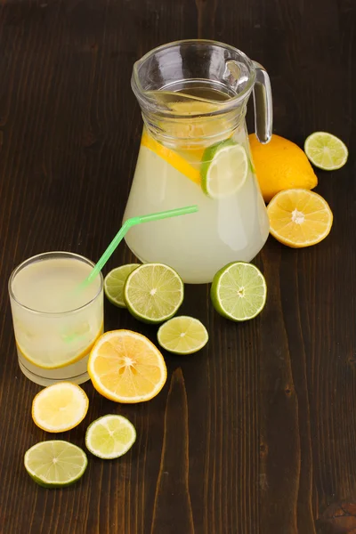 Limonada cítrica en vaso y jarra de cítricos alrededor en mesa de madera cerrar —  Fotos de Stock