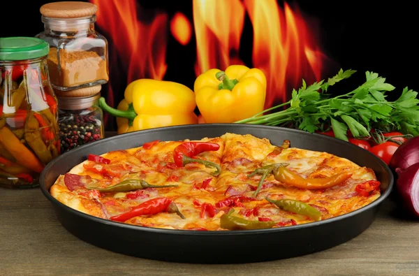 Leckere Pfefferoni-Pizza in der Pfanne mit Gemüse auf Flammenhintergrund — Stockfoto