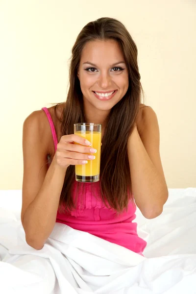 Joven hermosa mujer con vaso de jugo en la cama —  Fotos de Stock