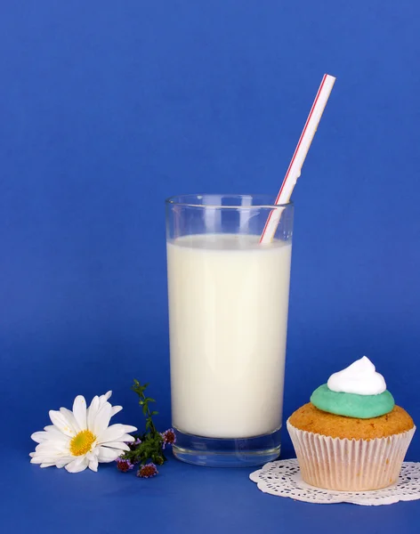 Glas frische neue Milch mit Kuchen auf blauem Hintergrund — Stockfoto