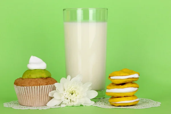 Glass of fresh new milk with cakes on green background — Stock Photo, Image
