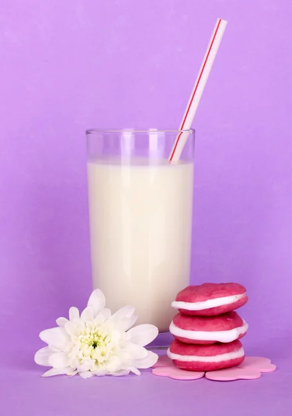 Glas frische neue Milch mit Kuchen auf violettem Hintergrund — Stockfoto