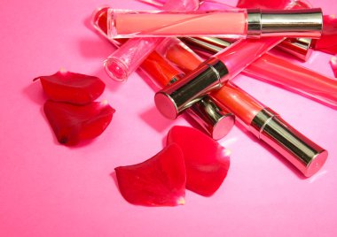 güzel dudak glosses pembe bir arka plan üzerinde gül yaprakları ile