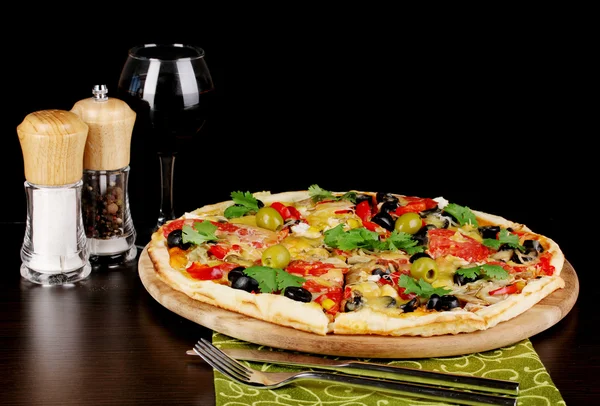 Heerlijke pizza met glas rode wijn en specerijen op houten tafel op zwart — Stockfoto