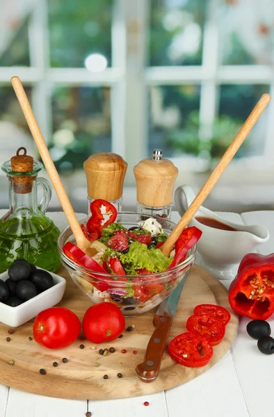 Salada grega fresca em taça de vidro cercada por ingredientes para cozinhar em wo — Fotografia de Stock
