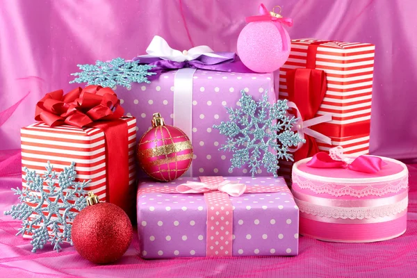 Färgstarka lila, rött och rosa presenter med julgranskulor och snöflingor på — Stockfoto