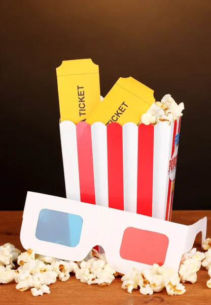 Popcorn med biljetter och bio glasögon på träbord på brun bakgrund — Stockfoto