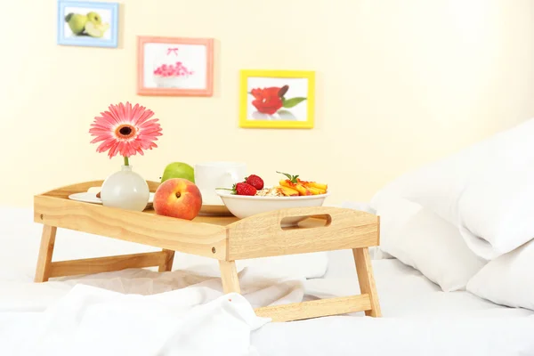 Houten dienblad met licht ontbijt op bed — Stockfoto