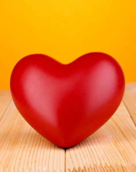 Decorative red heart on wooden table on orange background — Stock Photo, Image