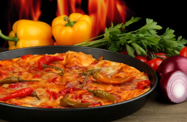 Tasty pepperoni pizza in pan with vegetables on flame background — Stock Photo, Image