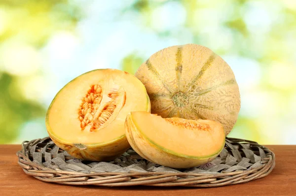 Cut melon on wicker mat on green background close-up — Stock Photo, Image