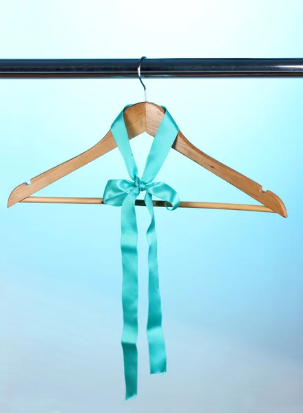 Beautiful turquoise bow hanging on wooden hanger on blue background — Stock Photo, Image