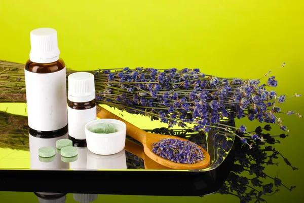 Garrafas de medicamentos e ervas no fundo verde. conceito de homeopatia — Fotografia de Stock