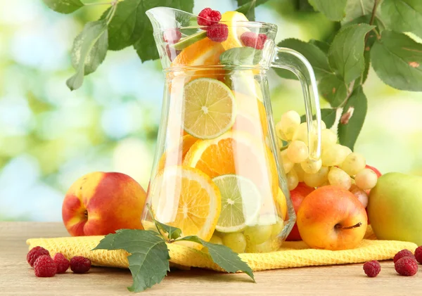 Jar with citrus fruits and raspberries, on green background — Stock Photo, Image