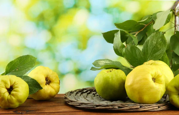 Süße Quitten mit Blättern, auf Holztisch, auf grünem Hintergrund — Stockfoto