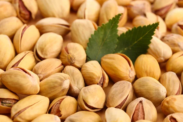 Tasty pistachio nuts with leaves, close up — Stock Photo, Image